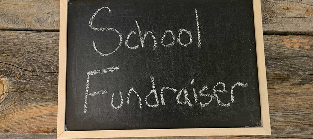 School fundraiser sign on wood wall.