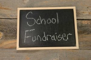 School fundraiser sign on wood wall.