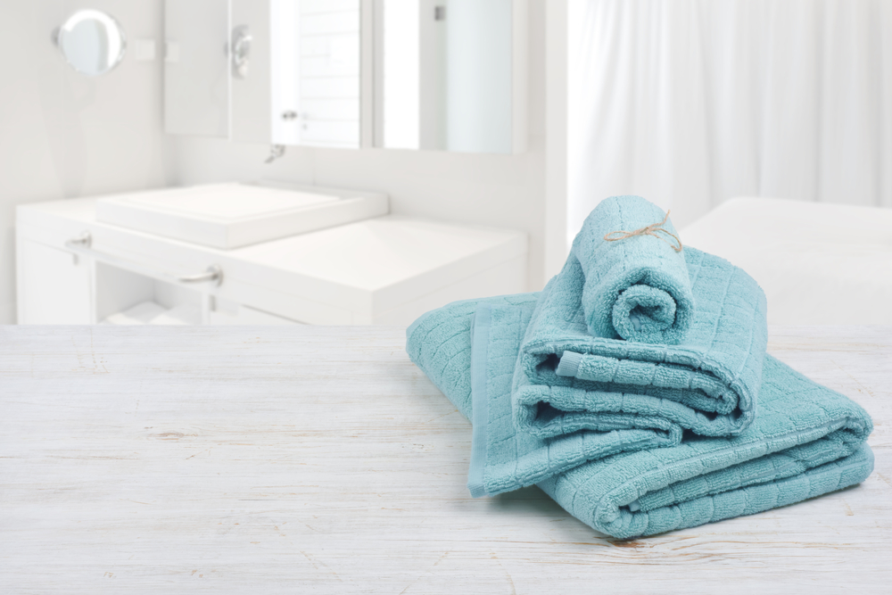 Clean aqua folded towels in white bathroom.