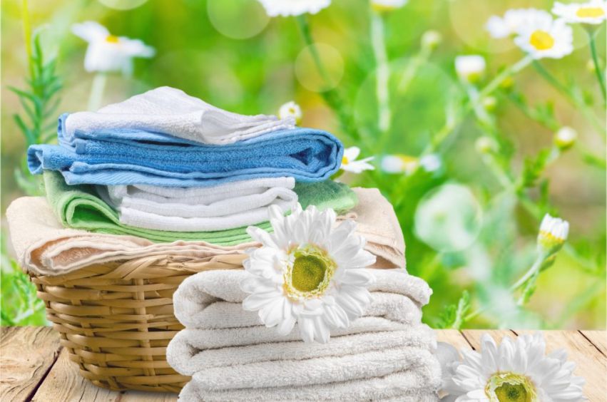Clean folded towels in basket on natural wood table.